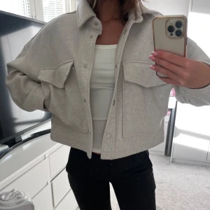 Ljus kappa - Säljer en ljus kappa från Stradivarius i storlek S i använd skick. Kappan har rymliga fickor och silvriga knappar fram. Den neutrala färgen gör den lätt att matcha med olika outfits!