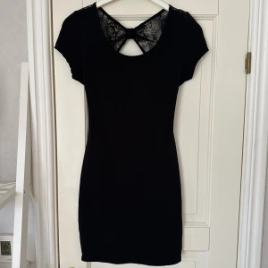 Kortärmad klänning med spetsdetalj - Svart kortärmad klänning med svart spetsdetalj baktill i storlek 40 från Tally Weijl. Använd ett fåtal gånger så i gott skick.