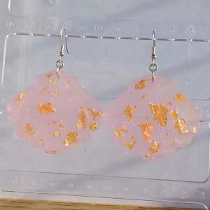 Säljer ett par supercoola rosa örhängen med guldfläckar. De har en unik form som påminner om moln och är perfekta för att ge lite extra bling till din outfit. Passar perfekt till både vardag och fest! Gjorda i resin. OBS bilden är ett exempel, viss färg/glitter skillnad kan förekomma.