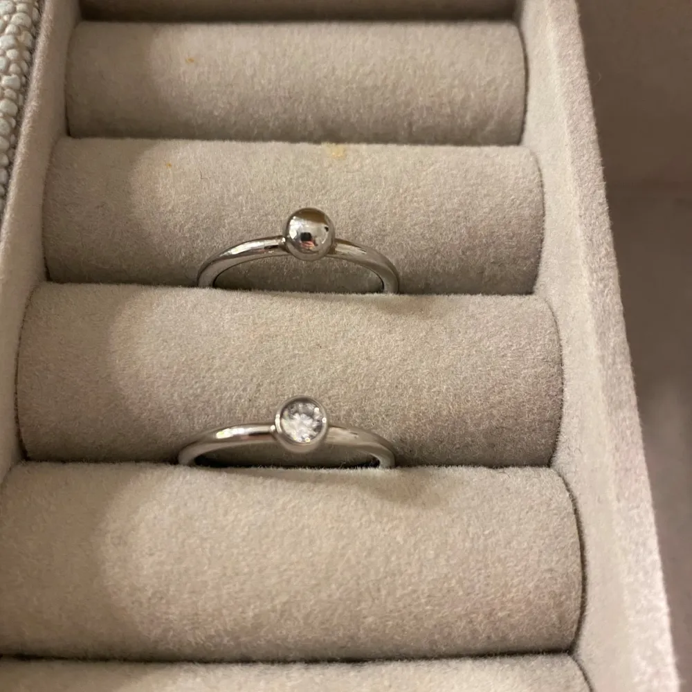 Säljer två stilrena silverringar. Den ena ringen har en rund silverkula och den andra en klar sten som ger en elegant touch. Perfekta för vardagen! De är från edblands äldre kollektion som inte finns längre, dom är i rostfrittstål!❤️. Accessoarer.