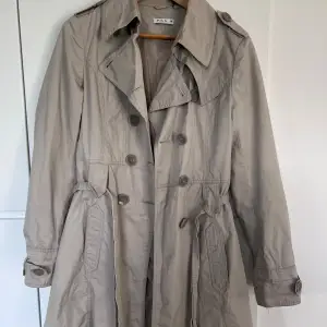 jättefin trenchcoat, perfekt längd (87cm från axel till nederkant). storlek M men passar snarare S/XS. köpt secondhand men oanvänd av mig