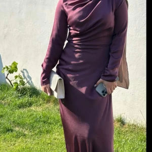 Balklänning - Säljer en elegant mörk vinröd långklänning. Klänningen har en tight passform och är långärmad, är endast använd en gång för bal! Materialet ser ut att vara mjukt och bekvämt, vilket gör den idealisk för både fest och mer formella tillfällen