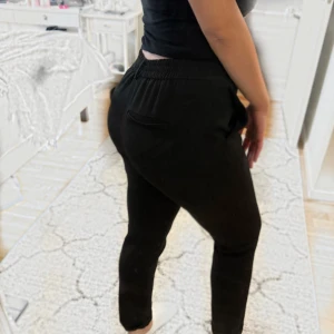 Svarta byxor  - Svarta byxor från Vero Moda i storlek S/32 med resår i midjan och praktiska sidofickor. Byxorna har en smal passform och är tillverkade i ett mjukt, bekvämt material som ger en elegant look men med känslan av mjukisbyxor. Perfekta för både vardagsbru