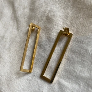 Rektangulära guldörhängen - Säljer ett par stilrena och moderna rektangulära örhängen i guld. De är perfekta för både vardag och fest och ger en elegant touch till vilken outfit som helst. Köpta i Barcelona. I nyskick, endast testade.