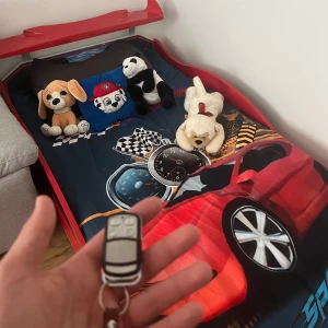 Bilsäng - Bilsäng till salu! Röd, perfekt för barn som älskar bilar. Utmärkt skick, ser ut som en sportbil.  Funktioner: LED-lampor styrda med fjärrkontroll, samt ljudfunktioner.  Material: Trä och tålig plast.  Pris: 3500 kr utan madrass