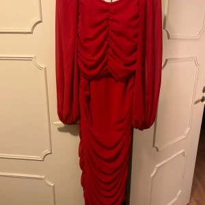 Röd festlig klänning❣️ - Superfin röd draperad klänning med lösa ärmar, går ner till vaderna och sitter såå fint på kroppen, strl L men passar en M också. Använt 1 gång i somras, nytvättad och i nyskick. Perfekt till festliga tillfällen eller bara en finare middag❤️‍🔥