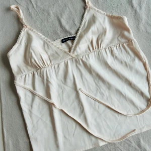 Ljusaprikost silkigt linne  Brandy Melville💕 - Nyinköpt, oanvänt silkigt linne från Brandy Melville, ljust aprikost. Knytband  samt reglerbara axelband. Blev ett felköp men hann klippa bort lappen. Pris 285:- i butik, säljes för 160:- 