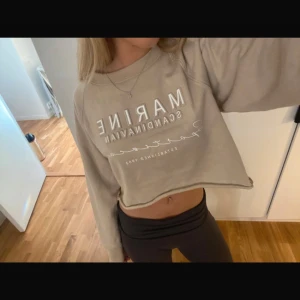 Beige croppad sweatshirt från Marine Scandinavian - Säljer en beige croppad sweatshirt från Marine Scandinavian. Tröjan har långa ärmar och ett tryck framtill. Perfekt för en avslappnad stil. Jag har klippt av den själv längst ner för en mer croppad look