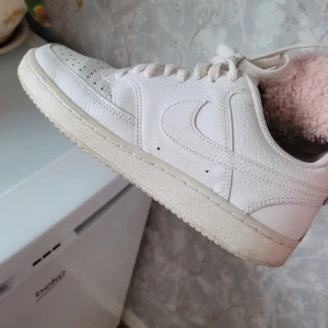 Vita Nike air force  - Säljer ett par vita Nike sneakers med klassisk design och snörning. Skorna har en stilren look med Nike-loggan på hälen och insidan. Perfekta för en casual stil.