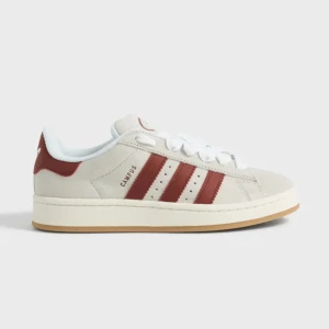 Adidas Campus sneakers i beige och röd - Snygga Adidas Campus sneakers i beige mocka med röda detaljer. Skorna har de klassiska tre ränderna på sidan och en bekväm gummisula. Perfekta för en stilren och sportig look.