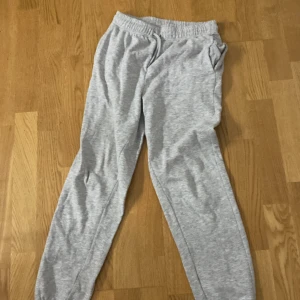 Grå mjukisbyxor från SOC - Säljer ett par bekväma grå mjukisbyxor från SOC. Byxorna har elastisk midja och är perfekta för en avslappnad dag hemma. De är tillverkade i ett mjukt material som känns skönt mot huden.