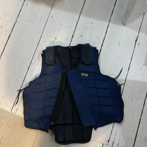 Blå skyddsväst från CRW - Säljer en blå skyddsväst från CRW i storlek XS. Västen har en quiltad design och är perfekt för ridning. Den är justerbar med snörning på sidorna för en bekväm passform.                                    ——————————————————— säljer mer ridutrustning på min profil ❤️