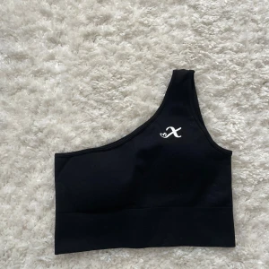 Svart oneshoulder topp från Xshape stl S - Snygg svart oneshoulder topp från Xshapes stl S, toppen har inlägg som även går att ta ut, kan nog passa en XS också, aldrig tränad i har bara legat i garderoben, köparen betalar frakt☺️