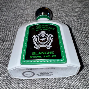 Derby Club House Blanche Eau de Parfum - Fräsch och aromatisk parfym för män från Armaf. Derby Club House Blanche har toppnoter av vatten, bergamott och apelsin, mellannoter av grönt te och svartvinbär, samt basnoter av mysk, galbanum och sandelträ. Flaskan är vit med gröna detaljer och rymmer 100 ml. Ca 95ml kvar. Tillverkad i Frankrike.