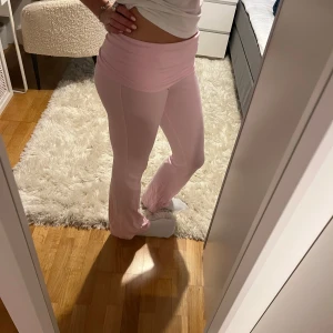 Rosa mjukisbyxor - Säljer ett par rosa yoga pants med låg midja. Byxorna har en bekväm passform och är perfekta för en avslappnad stil. De är tillverkade i ett mjukt material som gör dem sköna att bära.