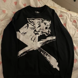 Svart långärmad tröja från Plein Sport - Snygg svart långärmad tröja från Plein Sport med ett stort vitt tryck av ett tigerhuvud och kors på framsidan. Perfekt för en cool och avslappnad stil.