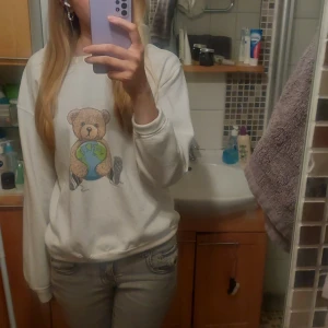 Vit sweatshirt med nalletryck - Säljer en vit sweatshirt med ett gulligt nalletryck från fashionbear. Tröjan har långa ärmar och en rund halsringning. Perfekt för en avslappnad stil. 