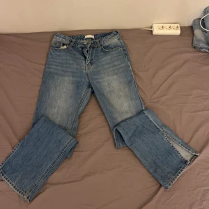 Blå jeansbyxor - Säljer ett par klassiska blå jeansbyxor med en rak passform. De har fem fickor och en knappgylf. Perfekta för en avslappnad stil.