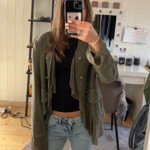 Olivgrön jacka/overshirt - Säljer en olivgrön jacka/overshirt från Walking Closet med silverknappar framtill och dekorativa fickor. Jackan är perfekt för höst och vår, men även för sommaren! Den har långa ärmar och detalj på ryggen💕 Köpt för 350kr