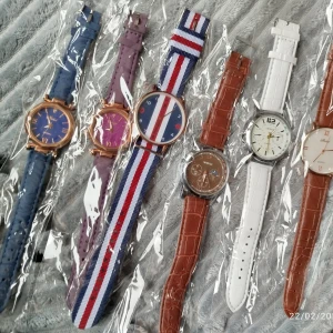 Flera stilrena klockor med olika armband - Säljer flera klockor med olika armband. Blått och lila skinnarmband, randigt tygarmband i rött, vitt och blått, samt brunt och vitt skinnarmband. Urtavlor i olika färger och stilar, inklusive en med romerska siffror och en med en kronografdesign.