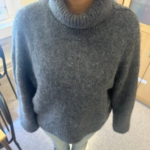 Mörkgrå stickad polotröja - Säljer en mysig mörkgrå stickad polotröja med hög krage.  jag är 164 och bär oftast S eller Xs för referens