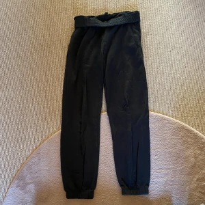 Svarta mjukisbyxor - Säljer ett par svarta mjukisbyxor med elastisk midja och muddar vid bensluten. Perfekta för en avslappnad stil och bekväma att bära. Byxorna har en enkel design utan extra detaljer.😻Om du vill ha en låg midja är det bara att vika ner kanten❤️Så bra att bara slänga på sig snabbt när du vill ha det mysigt💕Midja 37cm, innerbensläng 71cm!