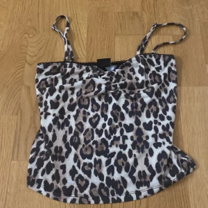 Leopardmönstrad linnetopp från Gina Tricot - Snygg leopardmönstrad linnetopp från Gina Tricot i storlek XS. Toppen har smala axelband och en liten rosett framtill. Säljer för att den inte passar mig. 