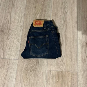 Mörkblå jeans från Levi's - Snygga mörkblå jeans från Levi's med klassisk femficksdesign och kontrasterande sömmar. Perfekta för en avslappnad stil. Märkeslappen syns tydligt på baksidan.
