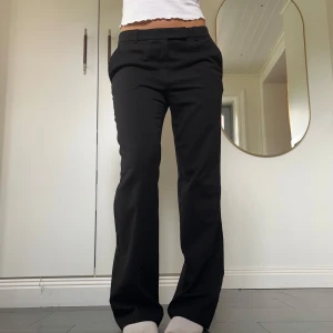Svarta lågmidjade kostymbyxor - Lågmidjade svarta kostymbyxor med bootcut från H&M i storlek 38. Fint skick. Tvärs över midjan är det 41 cm och innerbenslängden är ca 80 cm. Passar mig som är 172 och brukar ha S eller M. Använd gärna köp nu!