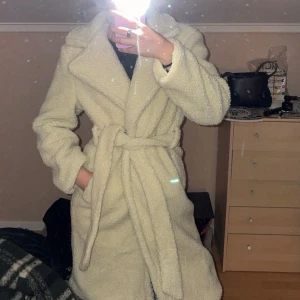 Kappa i teddy - Fin teddykappa från Nelly. Bältet på ena sidan har fläckar och ena fickan är trasig (se bilder). Att fickan är trasig är någon man knappt lägger märke till men lätt att fixa med nål och tråd. Bältet kan man ta bort om man vill det. Storlek XS/S ☺️