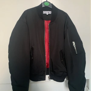 Svart bomberjacka från STAY - Säljer en snygg svart bomberjacka från STAY i storlek M men fungerar som S också. Ärmarna har en unik design, jackan har en cool röd insida och en dragkedja framtill, dessutom finns det en ficka med dragkedja på den vänstra ärmen. Jackan är begagnad men är i utmärkt skick, utan skador eller märken. En perfekt jacka för höst och vår! Vill man få fler bilder eller har några funderingar/frågor så kontakta gärna mig! Priset kan såklart diskuteras 🌼✨