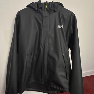 Helly hansen vind/regnjacka - Storlek 176/16 men kan även passa den som använder storlek S/M  Går att justera midjan med spännband och knappar vid armarna Använd ett par gånger Skick 8/10 Vid frågor skriv pm