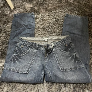 Blå jeans från Woman Soul - Säljer ett par snygga blå jeans från Woman Soul i storlek 36. De har en klassisk femficksdesign med stora framfickor och dekorativa sömmar på bakfickorna. Perfekta för vardagsbruk och kan enkelt matchas med olika toppar. Skicket är bra och de är bekväma att bära.
