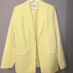 Gul kavaj från NA-KD - Säljer en superfin gul kavaj från NA-KD. Perfekt för våren och sommaren! Den har en klassisk design med långa ärmar och två fickor fram. Passar både till vardags och fest. Den är helt oanvänd!! 