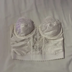 Vit korsett från Vassarette - Säljer en elegant vit korsett från Vassarette. Den har vackra spetsdetaljer och en klassisk design. B-cupa stolek S 
