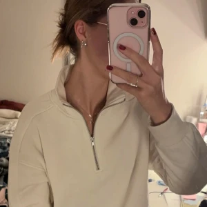 Vit tröja med dragkedja - Säljer en supermysig vit/cremefärgad tröja med halv dragkedja. Perfekt för chilliga dagar eller när du bara vill vara bekväm. Den har långa ärmar och en hög krage som du kan justera med dragkedjan. Passar perfekt till både jeans och mjukisbyxor. 🖤