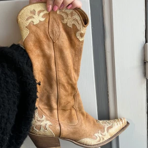 Cowboyboots - Supersnygga bruna cowboy boots i mocka med ljusa broderade detaljer och dragkedja på sidan. De har en robust klack och spetsig tå, vilket ger en klassisk western-look. Inköpta i Italien! Äkta mocka 🫶🏼