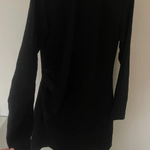 SVART MINIKLÄNNING  - Kort klänning från H&M men detalj vid midjan. Endast använd 1 gång. 