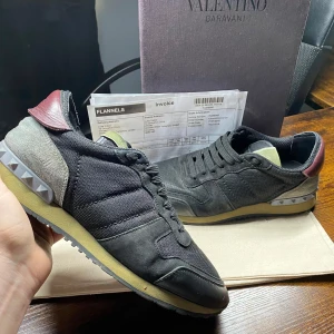 Valentino Rockrunners - Exklusiva Valentino Garavani Rockrunner sneakers! En perfekt kombination av lyx och streetwear, med premiumkvalitet och de ikoniska nitarna vid hälen. |  Färg: Camouflage (svart, röd, grå) 🖤🩶❤️ | Material: Mix av mocka och läder 🏆| Skick: Lätt använda🙌 | Storlek: 42 👌| Box: Originalbox, kvitto och dustbag medföljer 📦✨ | 🚚 Leverans: Skickas snabbt via PostNord eller instabox | 💬 Skicka ett meddelande vid frågor!