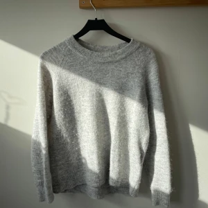 Grå stickad tröja från Selected Femme - Mysig grå stickad tröja från Selected Femme. Perfekt för kyliga dagar med sin mjuka och bekväma passform. Tröjan har långa ärmar och en rund halsringning. Tillverkad med omsorg för både stil och hållbarhet.💐🎧liten i storleken