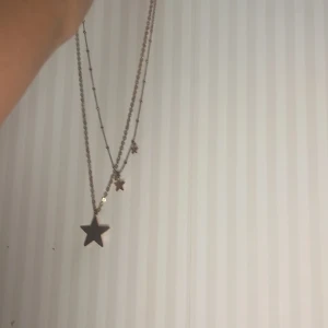 Silverfärgat halsband med stjärnor - Snyggt silverfärgat halsband med flera lager och stjärnberlocker. Perfekt för att ge en extra touch till din outfit. Kedjan är tunn och elegant, vilket gör det lätt att bära till olika tillfällen.
