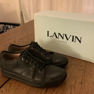 Lanvin Sneakers - Eleganta Svarta Lanvin sneakers i mycket gott skick (7/10). Extra skosnören medföljer för en personlig touch. Observera att originalboxen ej ingår.