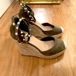 Kilklackar med nitar - Snygga khaki färgade kilklackar (12cm) med nitar runt ankeln i nytt skick!💕