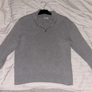 Grå stickad tröja från These Glory Days - Säljer en stilren grå stickad tröja från These Glory Days. Tröjan har en dragkedja vid halsen och långa ärmar. Perfekt för kyligare dagar. Inga tecken utav användning eller förutom (se sista bilden).