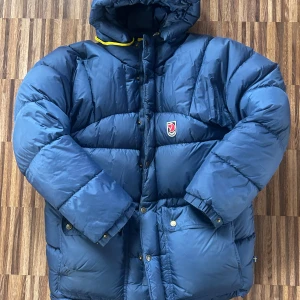 Blå dunjacka från Fjällräven - Säljer en blå dunjacka från fjällräven. Två små lagningar men inget som direkt syns. Annars jättebra skick! 