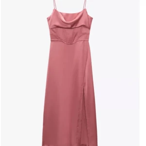 Rosa siden klänning med slits - Elegant rosa satin klänning med smala axelband och en slits. Den har en draperad urringning och markerad midja med en korsett liknande stil. Perfekt för speciella tillfällen. Några trådar som gått upp från tyget (se bilder) men syns knappt. Perfekt för fest,bal eller andra tillfällen!