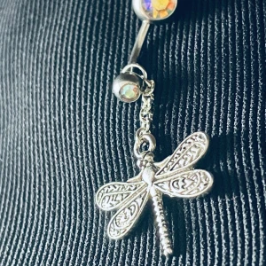 By prisförslag- Navelpiercing med trollslända - Snygg navelpiercing i silverfärg med en hängande trollslända. Piercingen har en glittrig kula som ger extra bling. Perfekt för att ge din stil en unik touch.