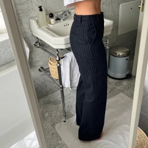 Blåa randiga kostymbyxor - Byxorna har en hög midja och en rak passform storlek 34