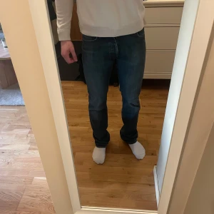 Mörkblå jeans från Acne - Säljer ett par snygga mörkblå jeans från Acne. De har en klassisk straight passform och är tillverkade i slitstarkt denim. Perfekta för en stilren look. Slitningar nertill på båda benen