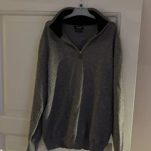 Grå halvzip i Kashmir  - Snygg grå tröja i kashmir med dragkedja och hög krage. Perfekt för kyligare dagar. Tröjan har långa ärmar och ribbade muddar vid ärmslut och nederkant.